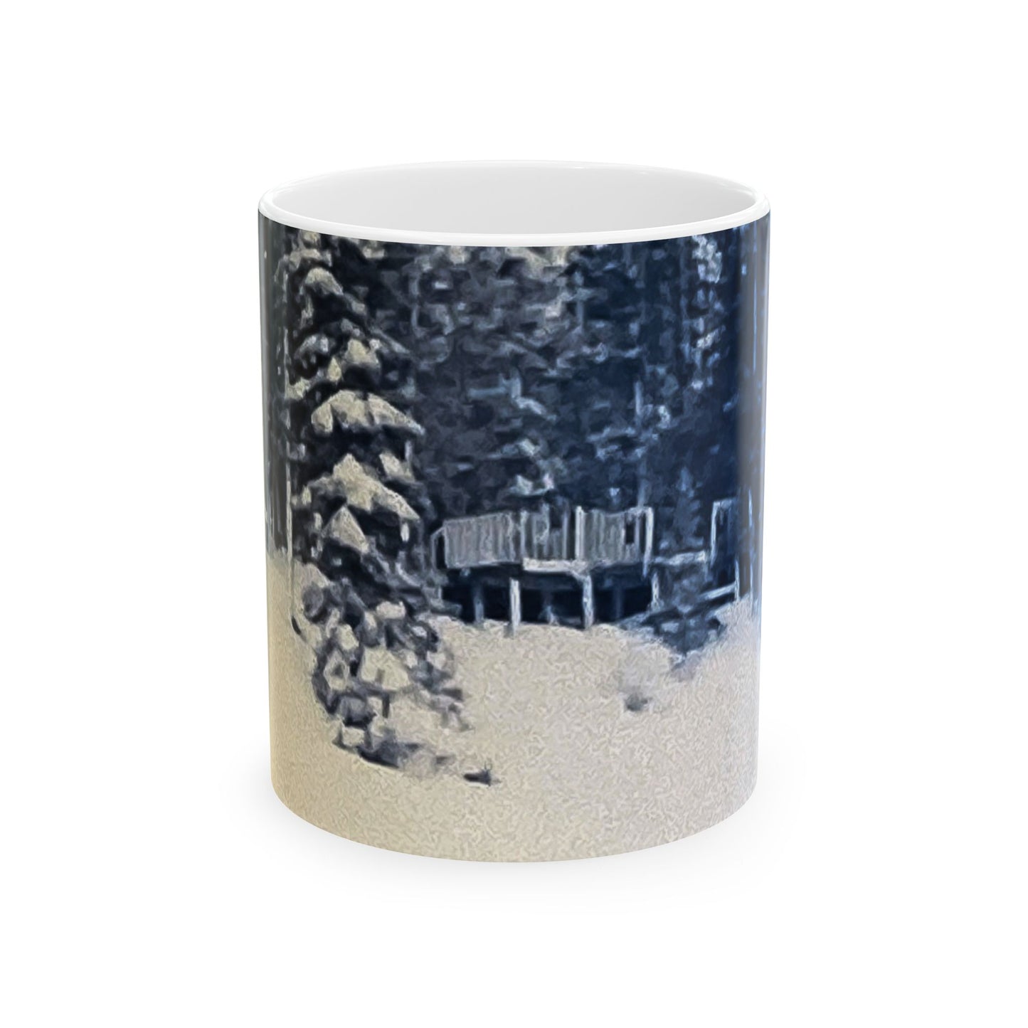 A white ceramic mug featuring a printed winter forest scene with snow-covered evergreen trees, a wooden bench, and a snowy foreground, shown on a plain white background.