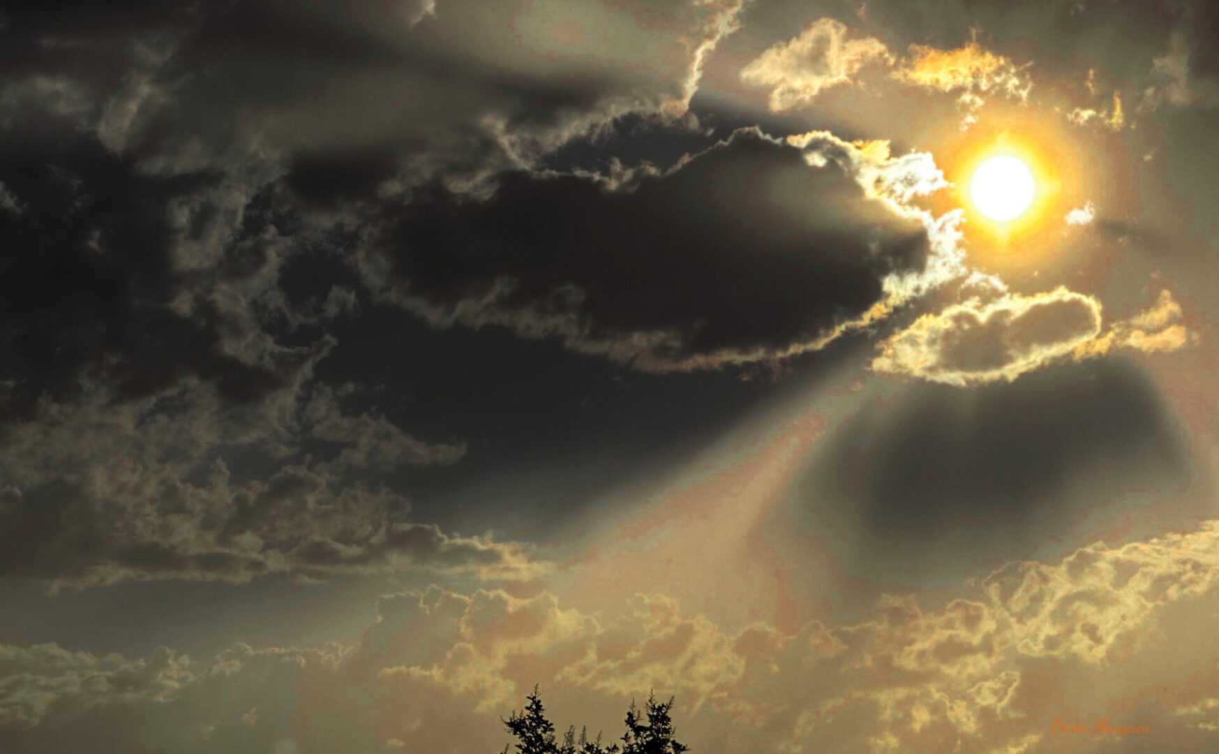 A sun behind the clouds with trees in front of it