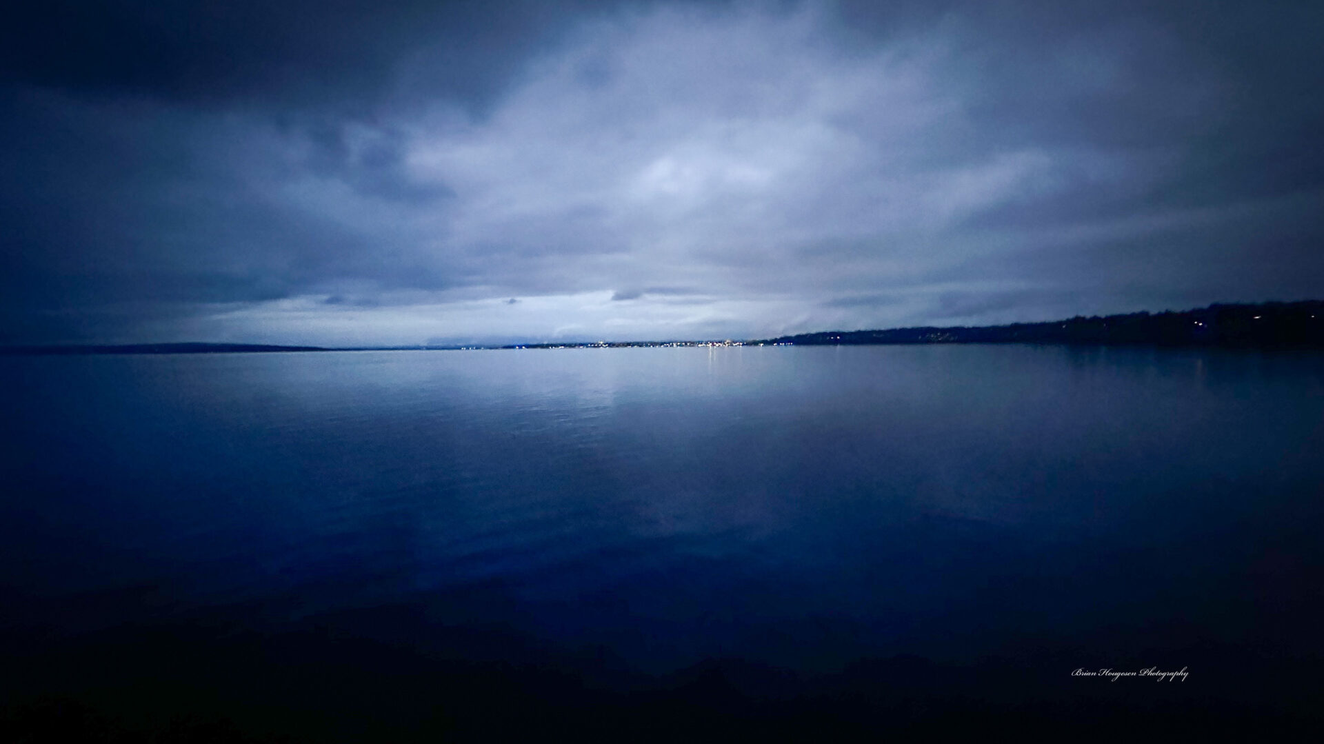 A body of water with dark clouds in the sky.