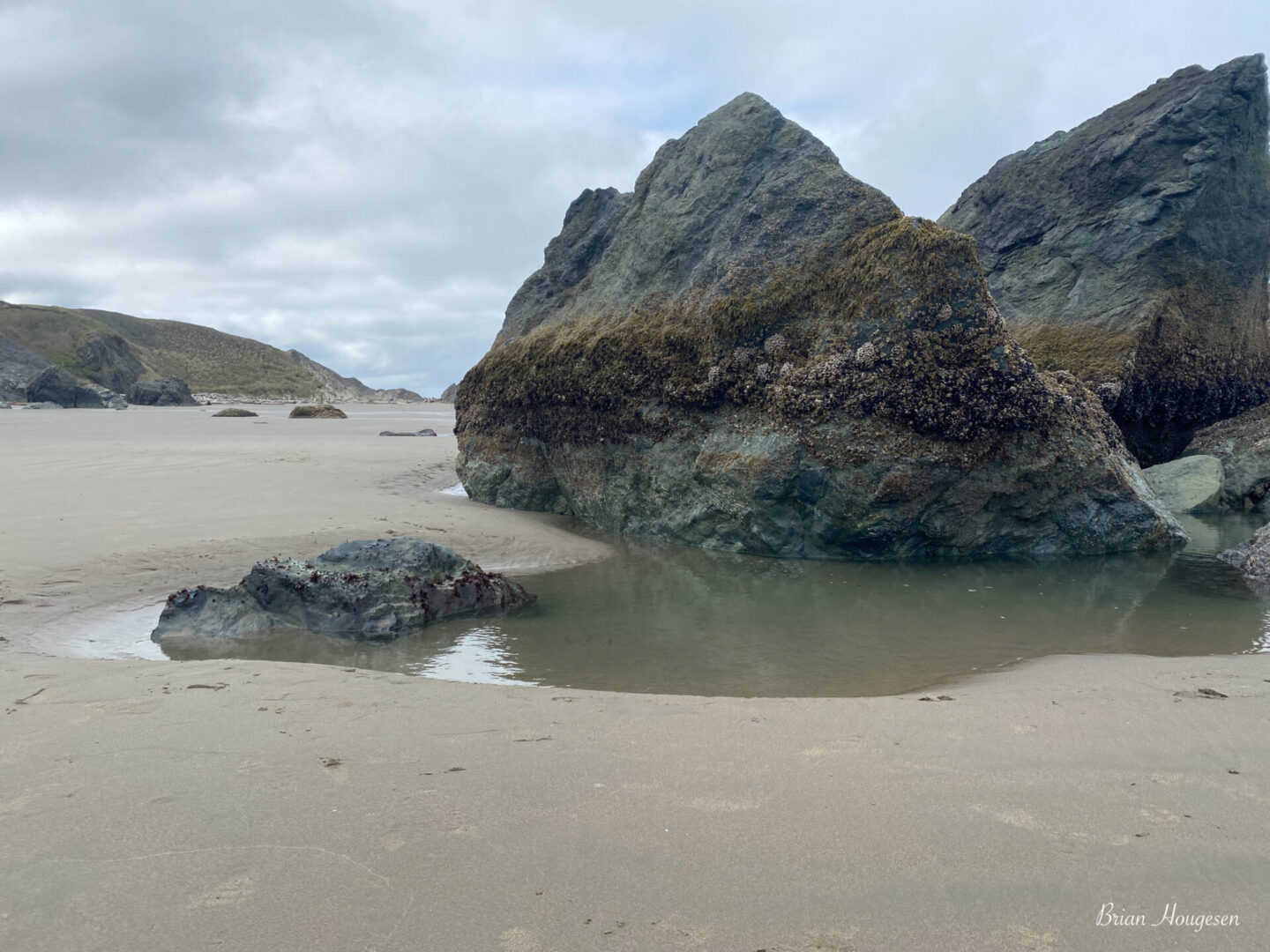 A rock formation on the beach with water