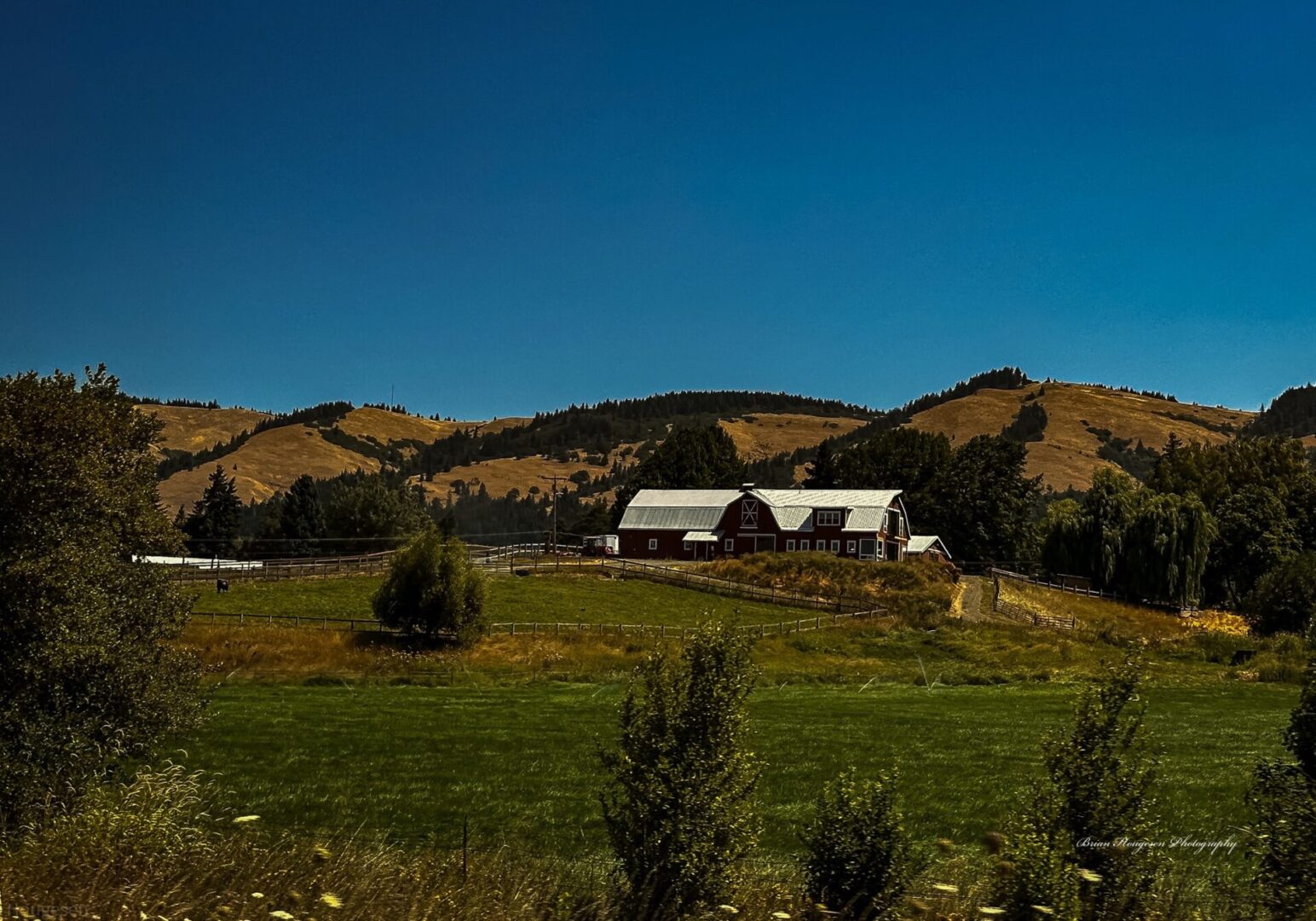 A barn sits in the middle of an open field.