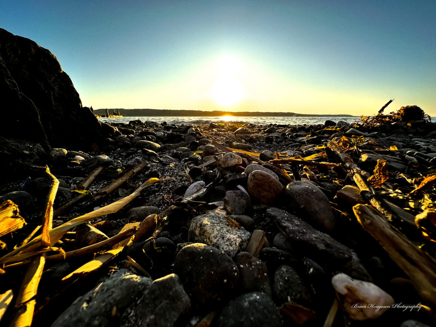 A beach with rocks and seaweed on the shore.