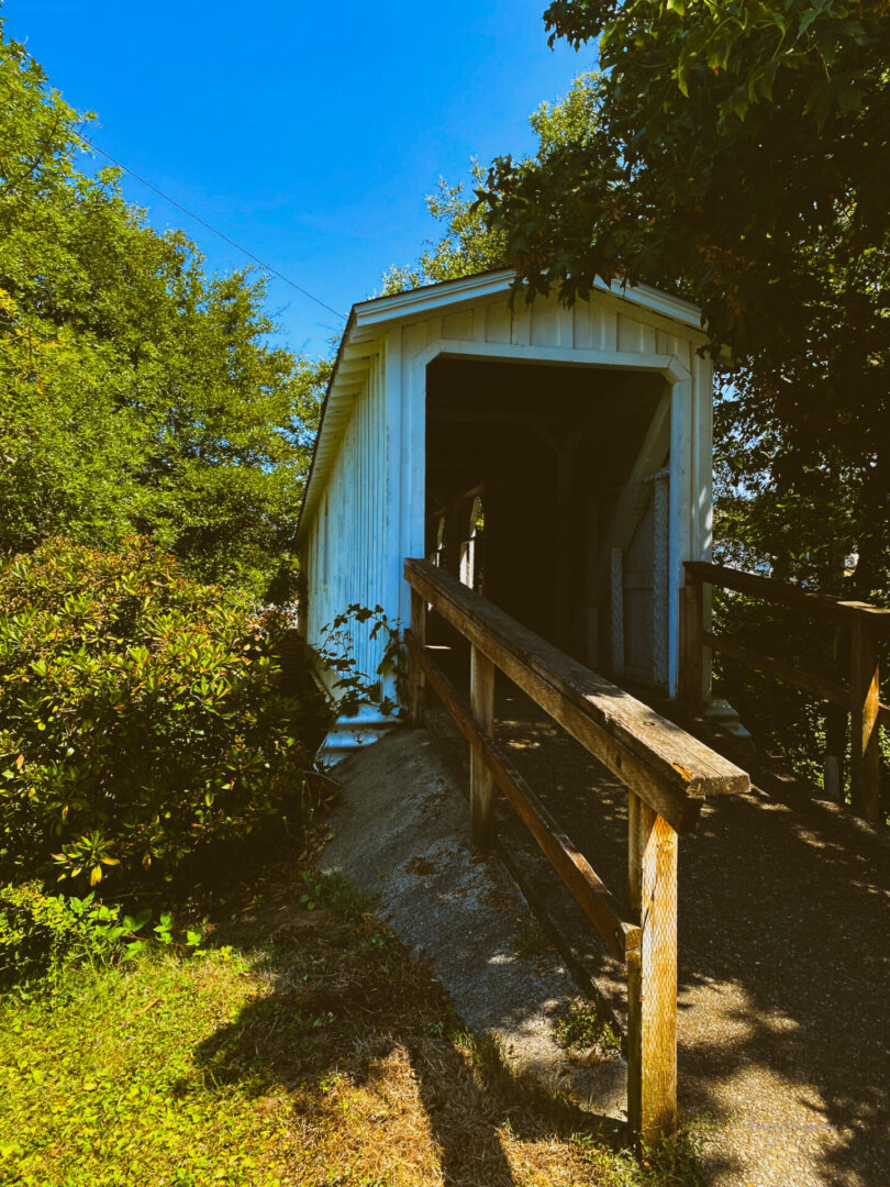 A white covered bridge with trees in the background.